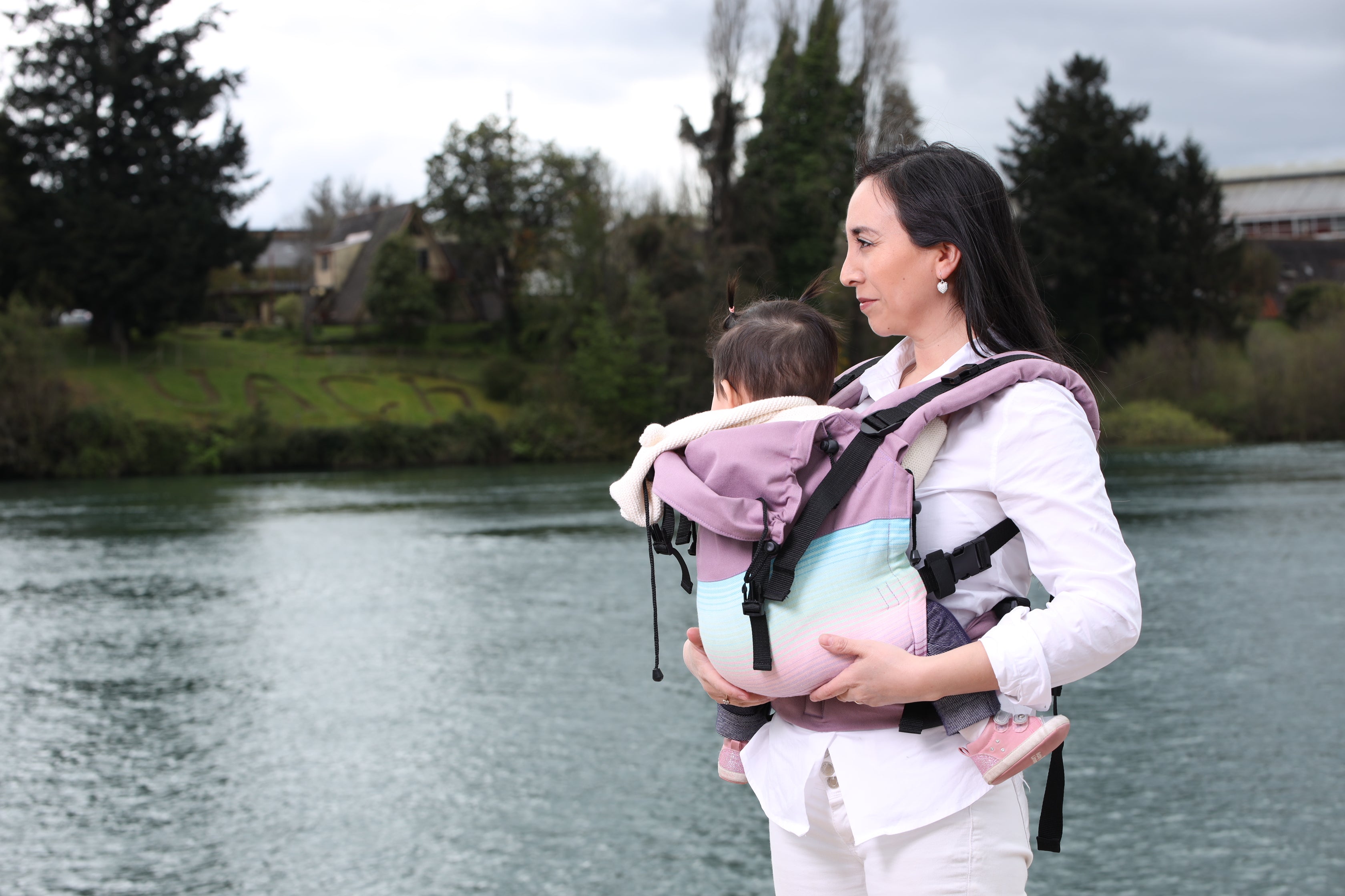 Mamá porteando a su guagua junto al río en Valdivia